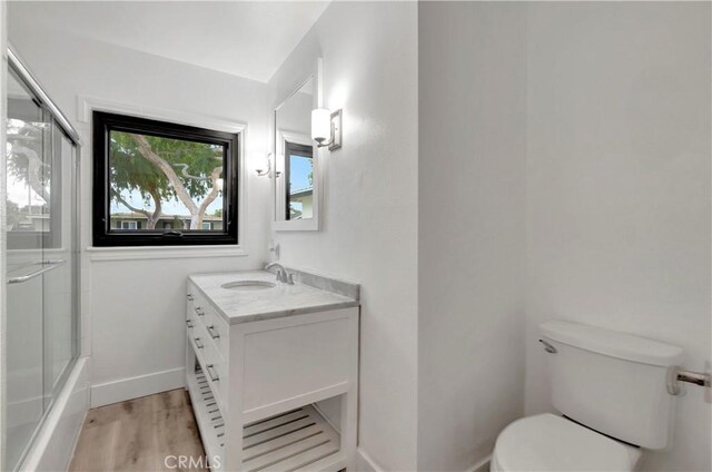 full bath featuring wood finished floors, toilet, vanity, and baseboards