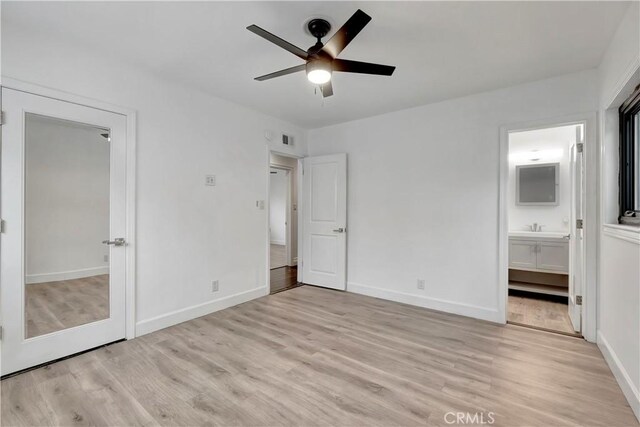 unfurnished bedroom featuring light wood-style flooring, baseboards, connected bathroom, and ceiling fan