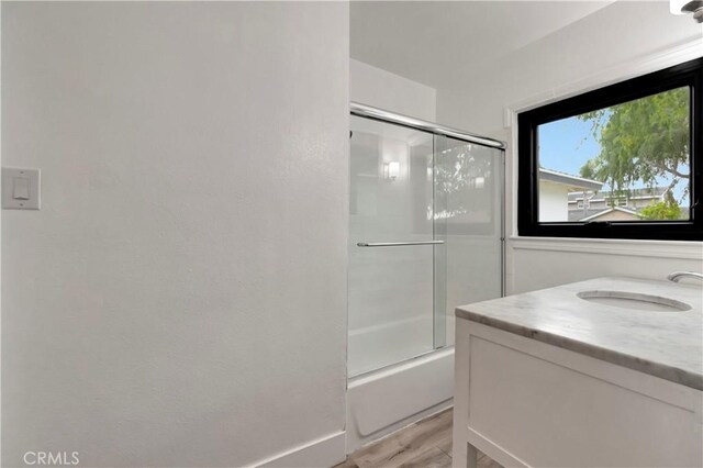 full bath with wood finished floors, combined bath / shower with glass door, and vanity