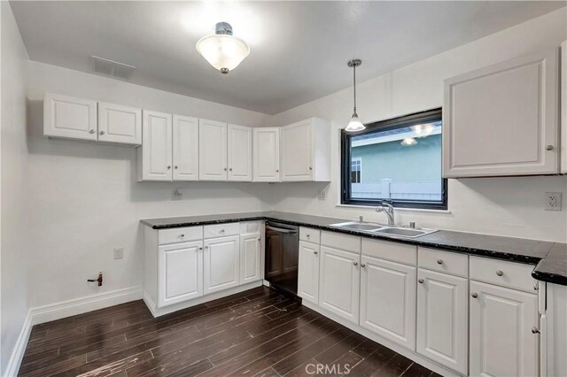 kitchen featuring dark countertops, dishwasher, white cabinets, and a sink