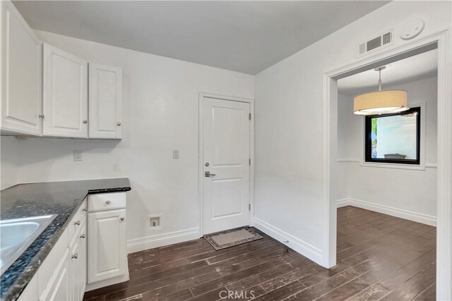 kitchen featuring dark wood-style flooring, dark countertops, white cabinets, and baseboards
