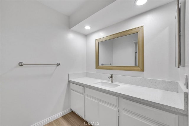 bathroom with vanity, wood finished floors, baseboards, and recessed lighting
