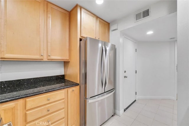 kitchen with freestanding refrigerator, light brown cabinetry, dark stone counters, light tile patterned floors, and recessed lighting