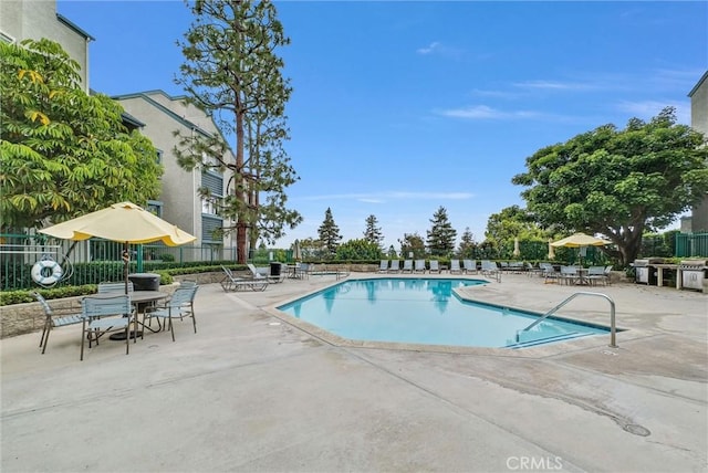 community pool with a patio and fence