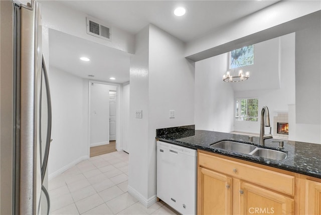 kitchen with freestanding refrigerator, dishwasher, a sink, dark stone counters, and recessed lighting