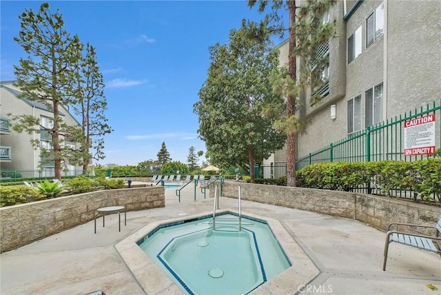 view of swimming pool with a hot tub, fence, and a patio area