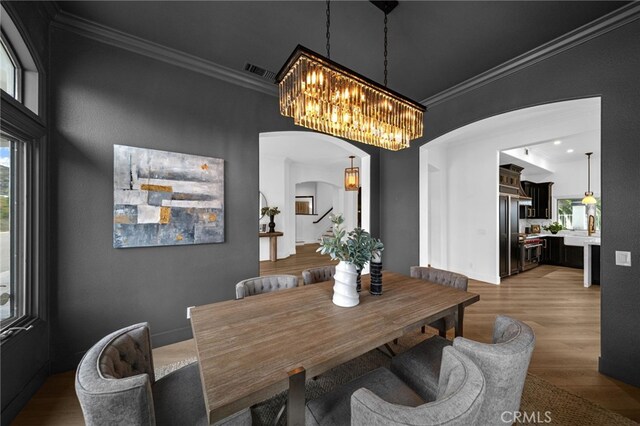 34105 Stage Rd, Temecula, CA 92592 - dining room featuring arched walkways, crown molding, a chandelier, and wood finished floors
