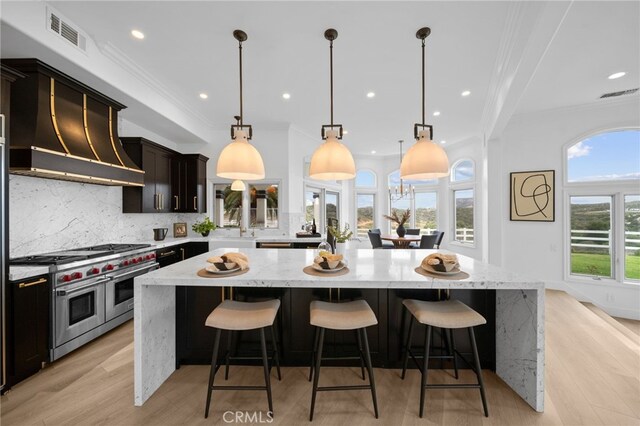 34105 Stage Rd, Temecula, CA 92592 - kitchen featuring double oven range, a large island, decorative backsplash, ornamental molding, and light stone counters