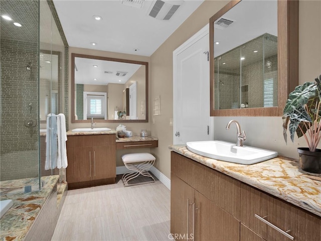 bathroom featuring a stall shower, two vanities, baseboards, and recessed lighting