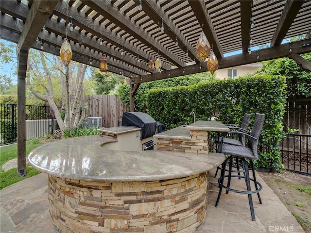 view of patio featuring a fenced backyard, grilling area, exterior kitchen, and a pergola