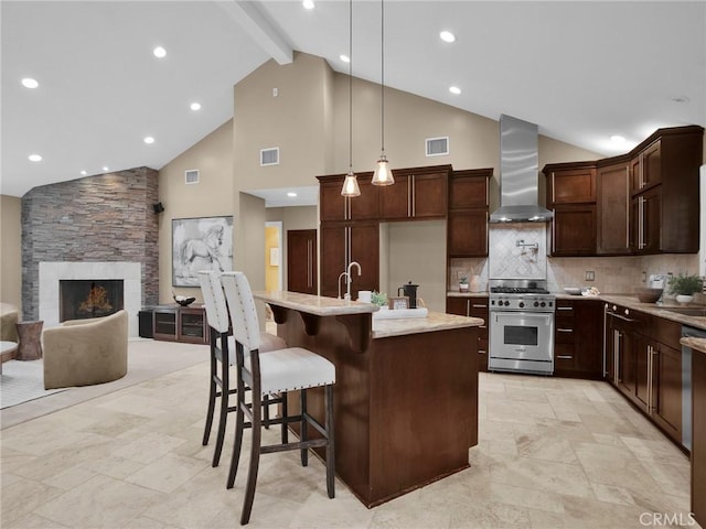 kitchen featuring high end stainless steel range, wall chimney range hood, high vaulted ceiling, beamed ceiling, and a stone fireplace
