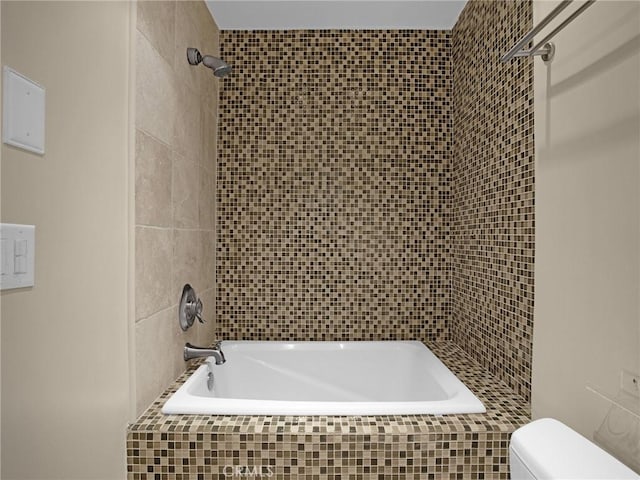 bathroom with toilet and tiled shower / bath