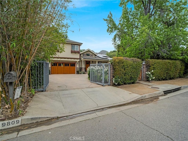 traditional-style home with an attached garage, a gate, concrete driveway, and a fenced front yard