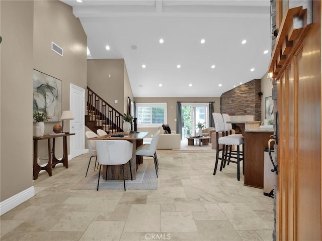 dining room featuring high vaulted ceiling, stairs, stone tile floors, baseboards, and recessed lighting