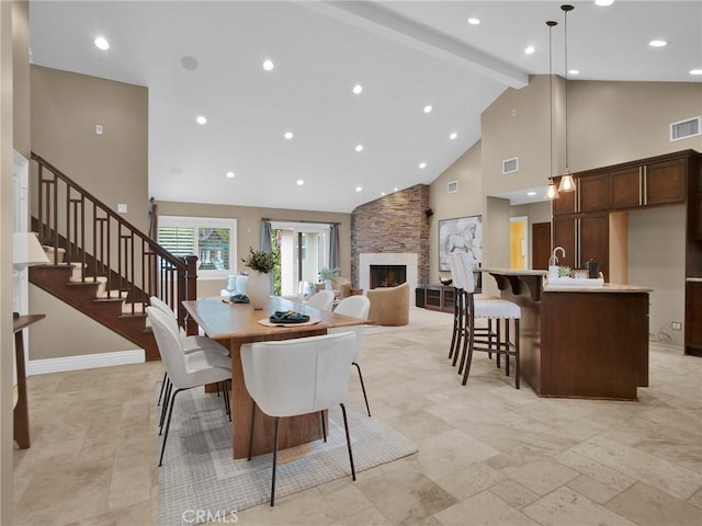 dining space featuring high vaulted ceiling, a fireplace, beamed ceiling, recessed lighting, and stairs
