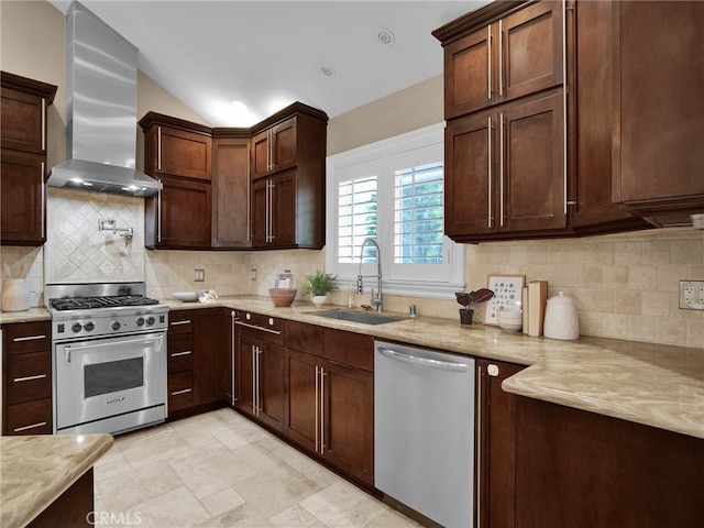 kitchen featuring appliances with stainless steel finishes, a sink, wall chimney exhaust hood, backsplash, and dark brown cabinetry