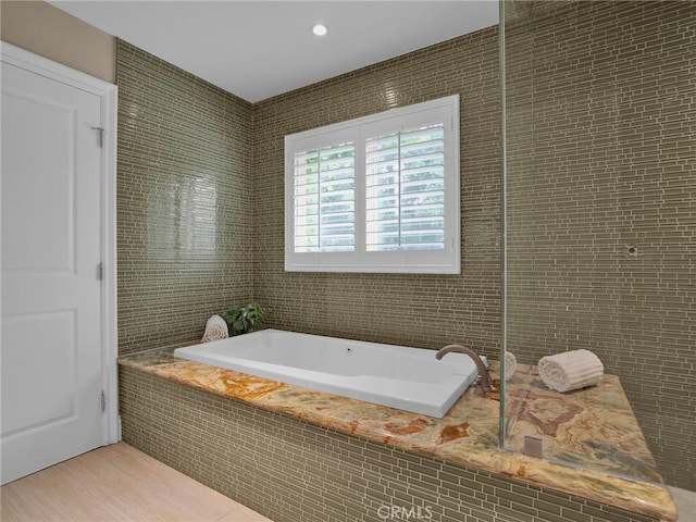 full bathroom featuring a bath, tile walls, and wood finished floors