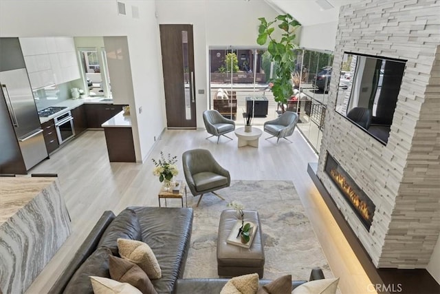 29 W Neapolitan Ln, Long Beach, CA 90803 - living area featuring light wood-type flooring, a stone fireplace, high vaulted ceiling, and baseboards