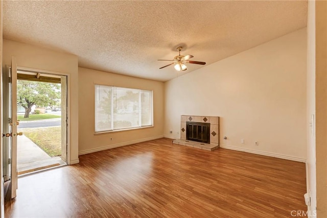 23719 White Owl Ct, Moreno Valley, CA 92553 - unfurnished living room with wood finished floors, a ceiling fan, a textured ceiling, baseboards, and a tiled fireplace