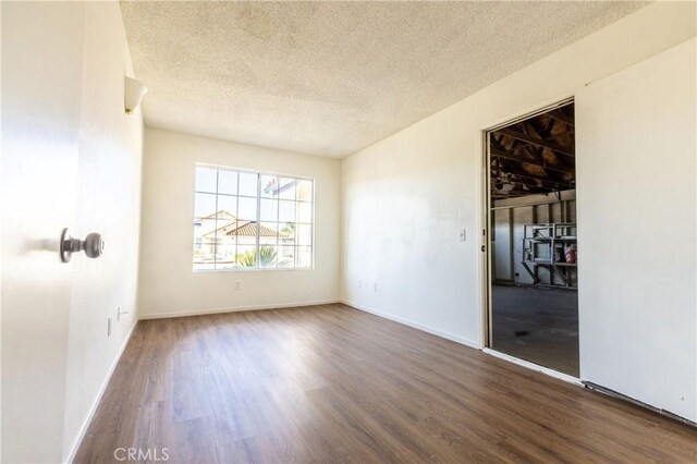 unfurnished room featuring wood finished floors, a textured ceiling, and baseboards