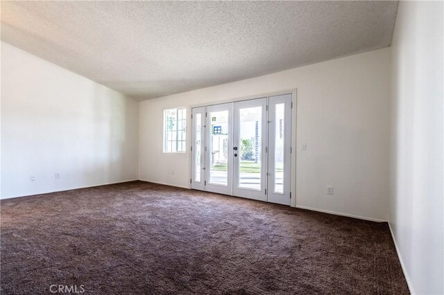 carpeted empty room with a textured ceiling, french doors, and baseboards
