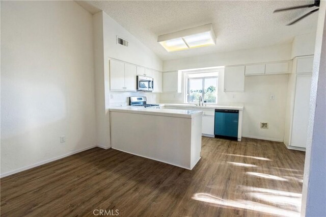 kitchen featuring appliances with stainless steel finishes, a textured ceiling, a peninsula, wood finished floors, and white cabinetry