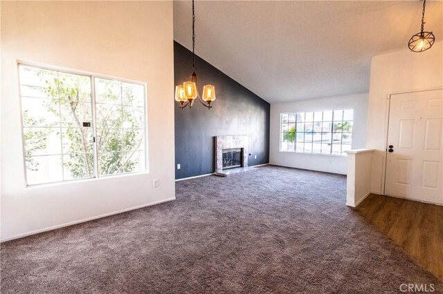 unfurnished living room with carpet flooring, a chandelier, baseboards, high vaulted ceiling, and a high end fireplace