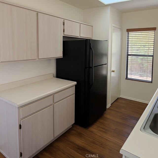 17795 Stevens Rd, Adelanto, CA 92301 - kitchen with freestanding refrigerator, dark wood finished floors, light countertops, baseboards, and a skylight