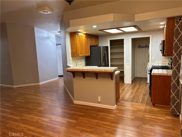 14749 Vassar Ct, Magalia, CA 95954 - kitchen with tile countertops, refrigerator with ice dispenser, a peninsula, brown cabinetry, and recessed lighting