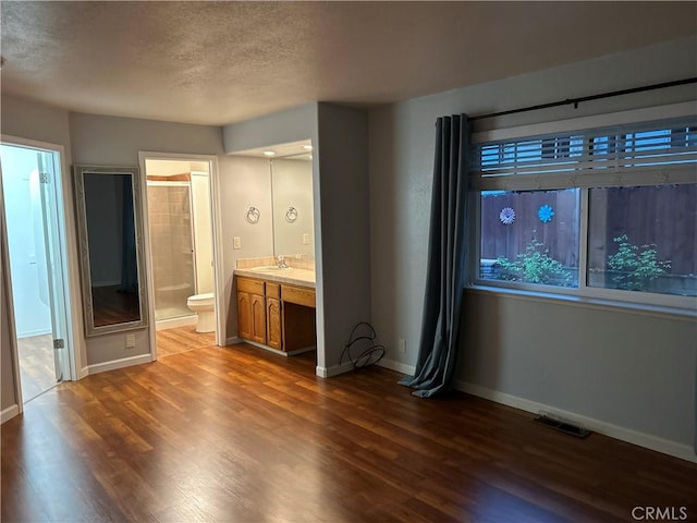 14749 Vassar Ct, Magalia, CA 95954 - unfurnished bedroom featuring a textured ceiling, baseboards, wood finished floors, a sink, and connected bathroom
