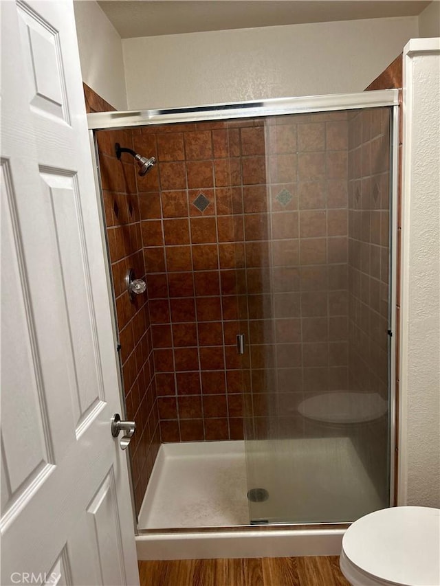 14749 Vassar Ct, Magalia, CA 95954 - bathroom with a shower stall, toilet, wood finished floors, and a textured wall