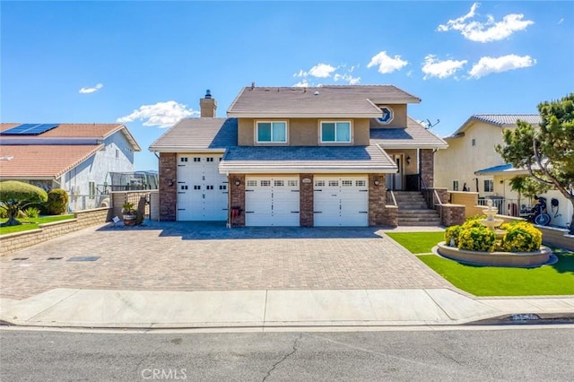 13545 Anchor Dr, Victorville, CA 92395 - view of front of property with decorative driveway, a chimney, an attached garage, and brick siding