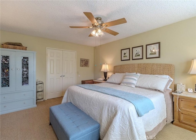 bedroom with light colored carpet, a ceiling fan, a textured ceiling, and a closet