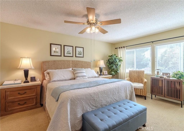 bedroom featuring light carpet, a textured ceiling, and ceiling fan