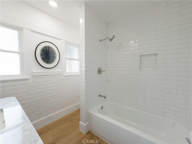 bathroom featuring wood finished floors,  shower combination, and healthy amount of natural light