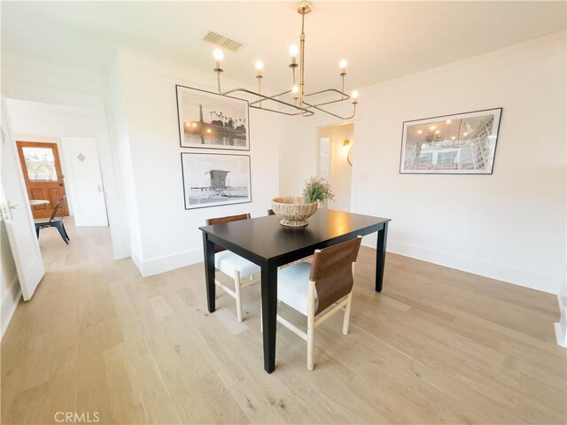 dining space with a chandelier, light wood-style floors, and baseboards