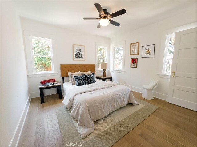 bedroom with wood finished floors, baseboards, and a ceiling fan