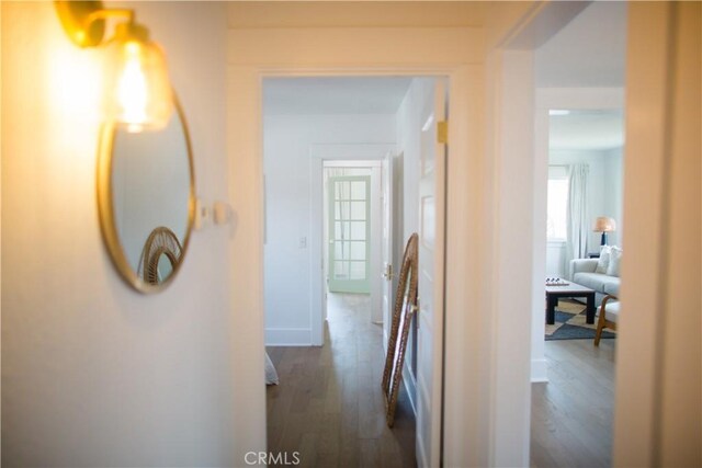hallway featuring wood finished floors, baseboards, and healthy amount of natural light