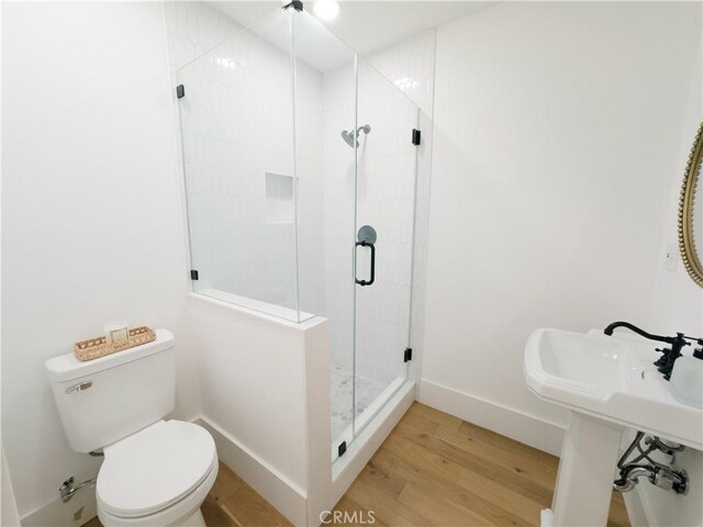 full bathroom featuring wood finished floors, toilet, a stall shower, and baseboards