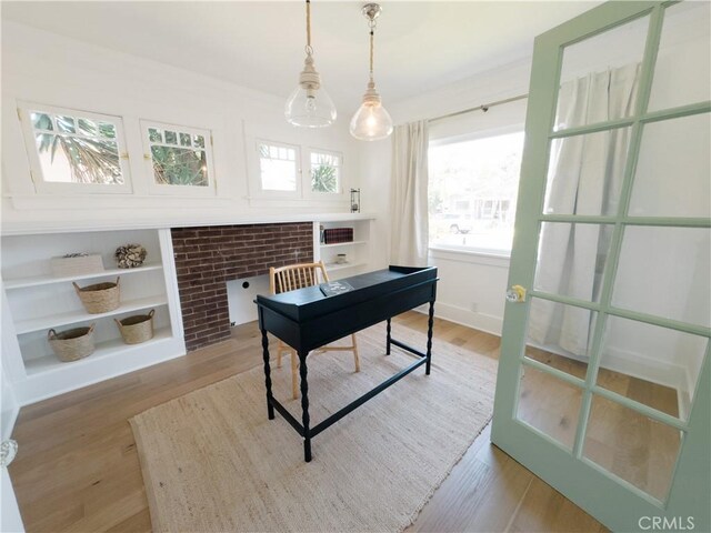 home office with healthy amount of natural light, wood finished floors, a fireplace, and built in shelves