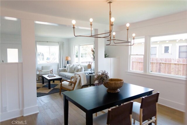 dining area featuring a chandelier, wood finished floors, and baseboards