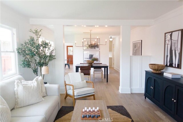 living area with light wood-style floors, a chandelier, and baseboards