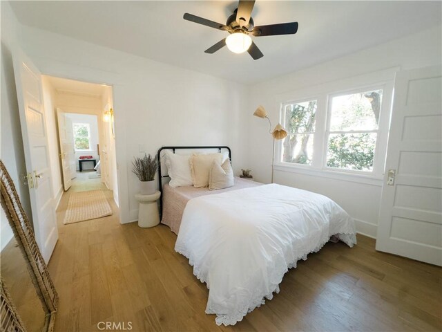 bedroom featuring light wood finished floors, ceiling fan, and baseboards