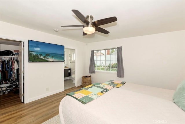 bedroom with a spacious closet, wood finished floors, a closet, ceiling fan, and connected bathroom
