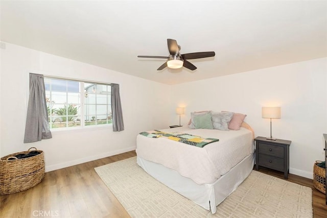 bedroom featuring wood finished floors, baseboards, and ceiling fan