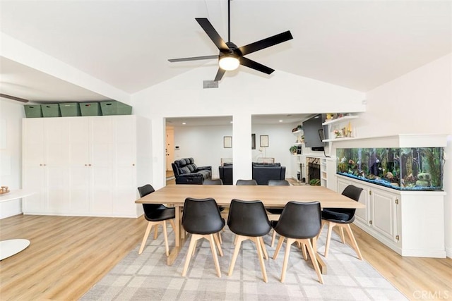 dining room with a ceiling fan, light wood finished floors, and high vaulted ceiling