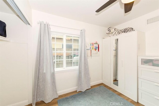empty room with wood finished floors, a ceiling fan, and baseboards