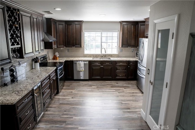 6338 Countryside Ct, Orland, CA 95963 - kitchen with appliances with stainless steel finishes, a sink, light wood finished floors, wall chimney exhaust hood, and decorative backsplash