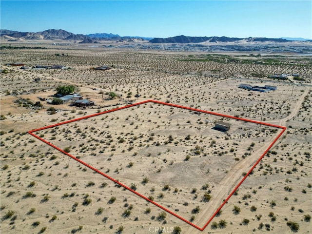 aerial view of sparsely populated area featuring property parcel outlined, a desert landscape, and a mountain backdrop
