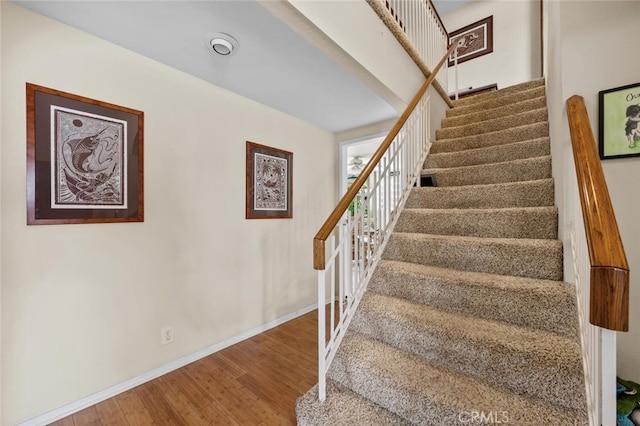 staircase with wood finished floors and baseboards